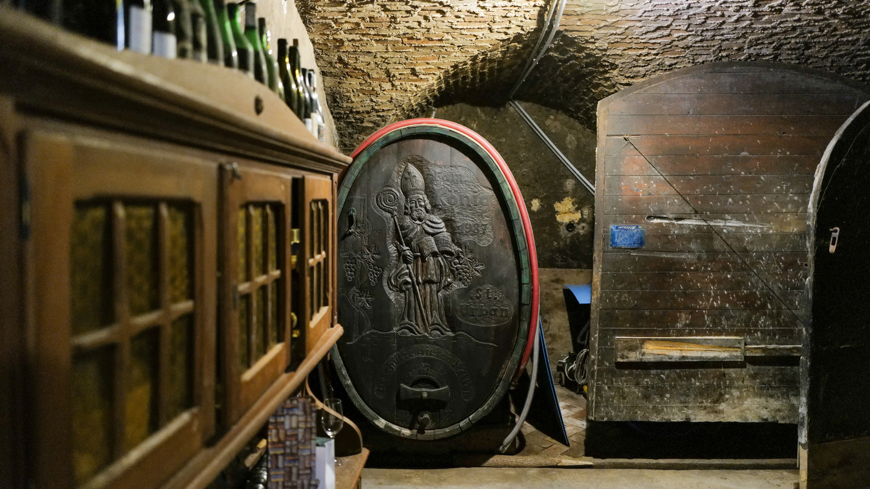 Wine barrels in a wine cellar with a focus on one barrel featuring a logo.